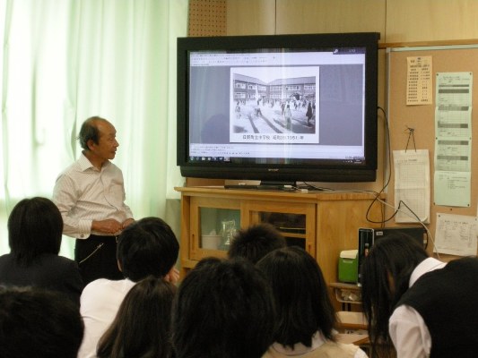 中学校付近の古い写真を見ながら解説する安西さん