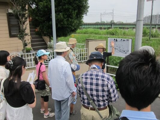 多摩川鉄橋の手前に展示された写真パネルを前にして