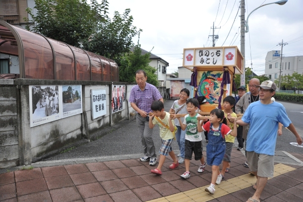 ひのっち神輿　新奥多摩街道入口交差点付近　左の塀には昔の写真が展示されています